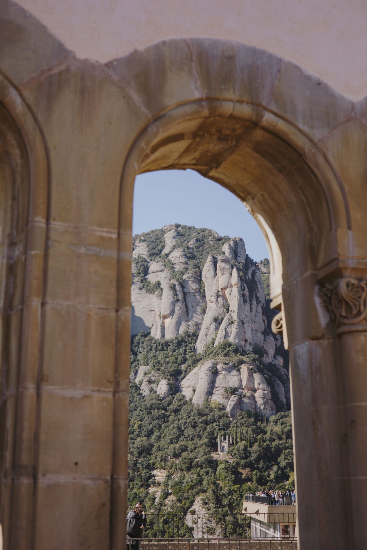 Arcades de pedra amb vistes a les muntanyes des d’un mirador, amb llum clara i ombres marcades al terra.