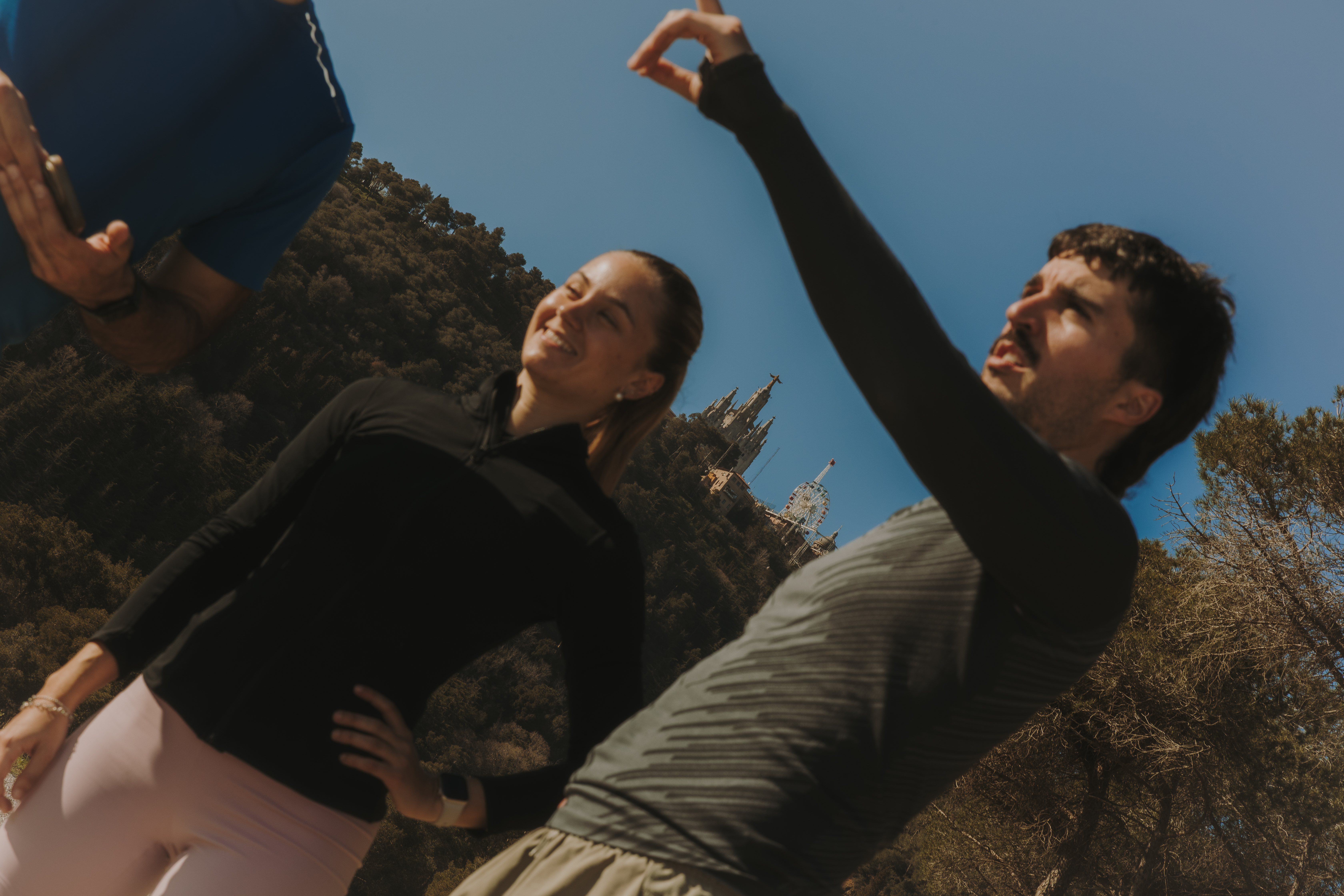 Two people talking in a wooded area, while one of them points into the distance.
