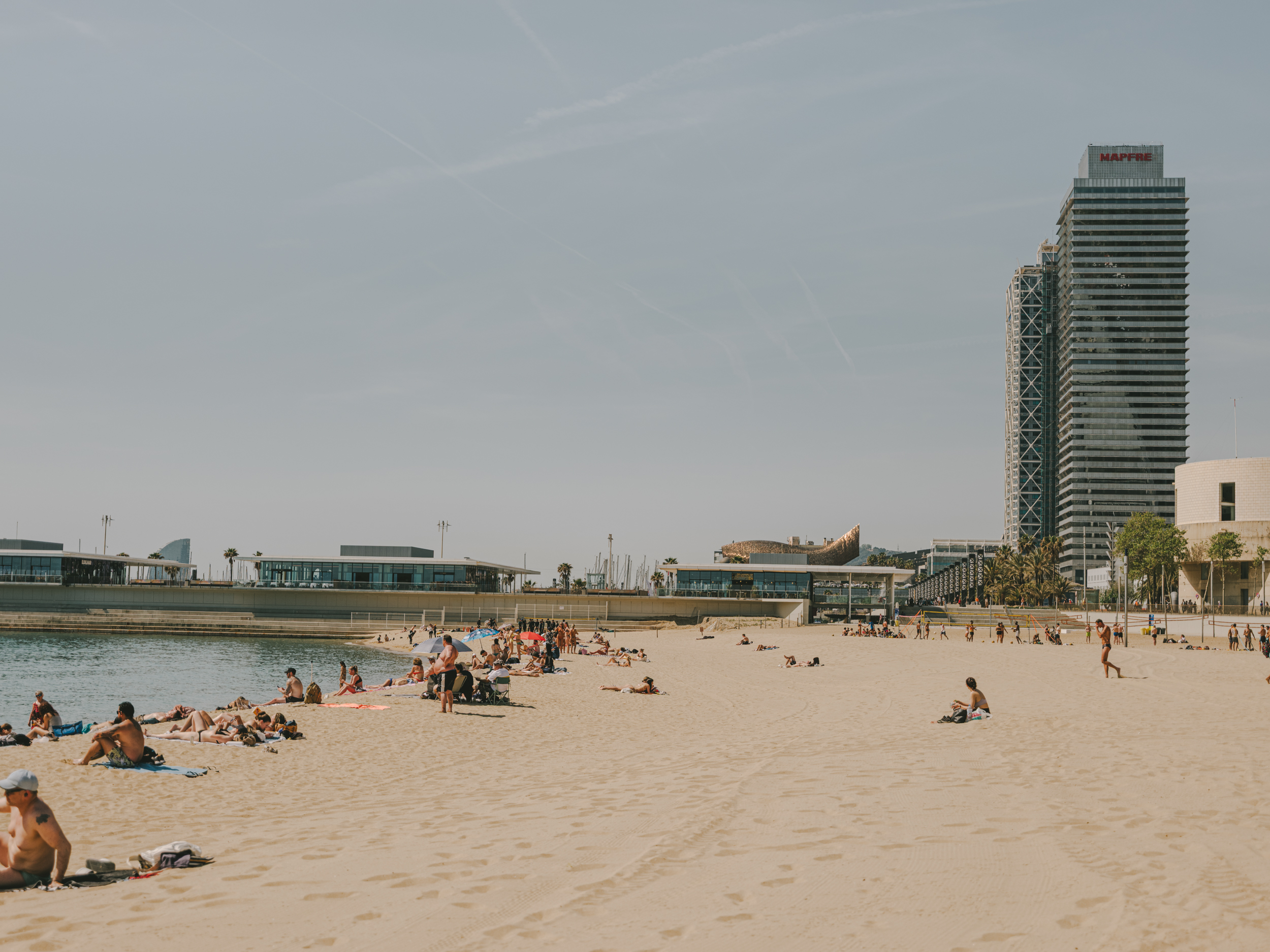 Beachgoers on the beach with Torre Mapfre and Gehry’s Fish in the background.